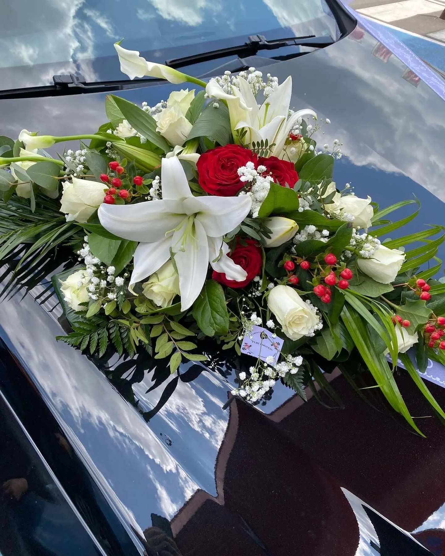 Décoration florale de voiture de mariage : lys blancs, roses rouges et blanches, gypsophile
